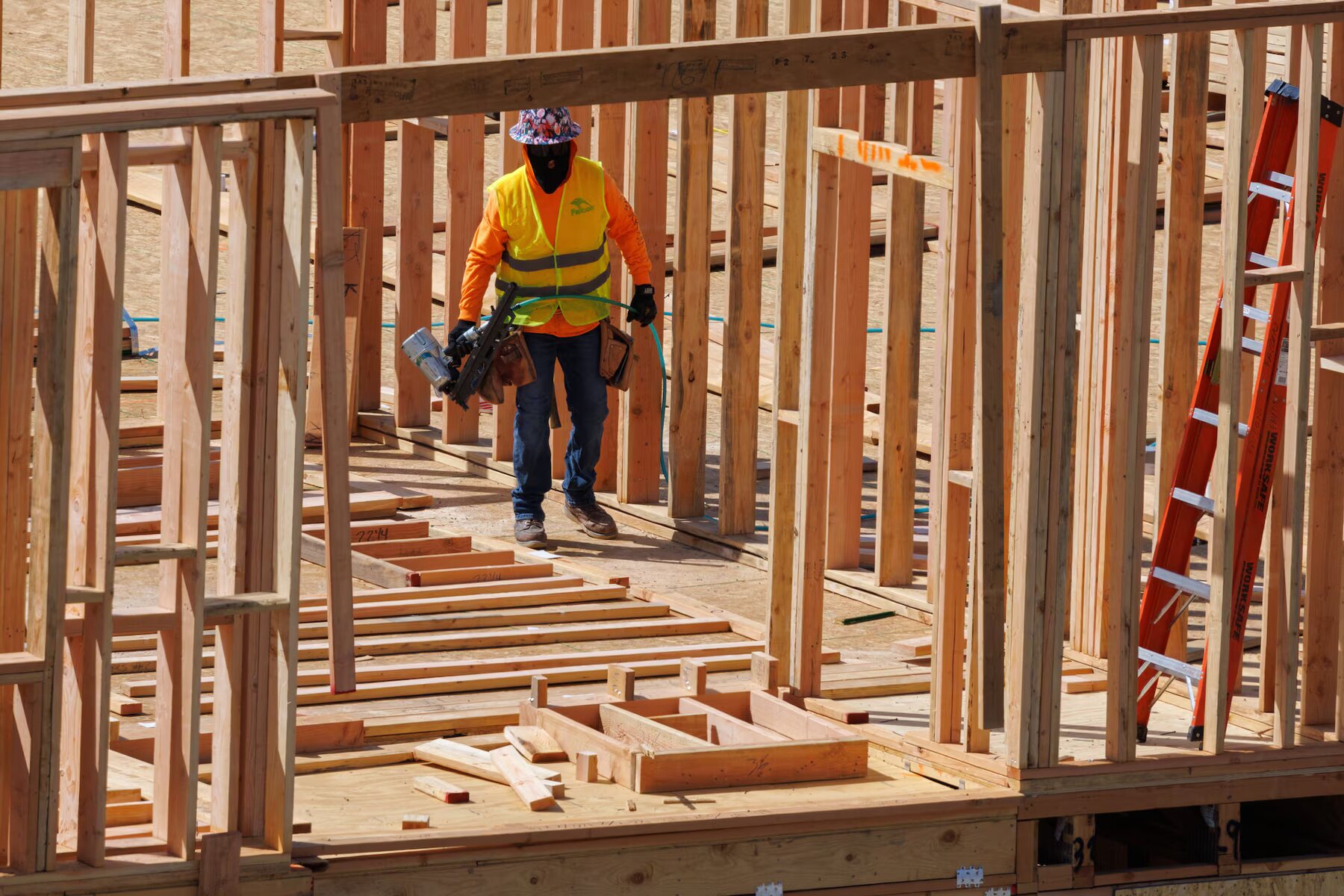A worker moving through the timber framing of a building under construction
